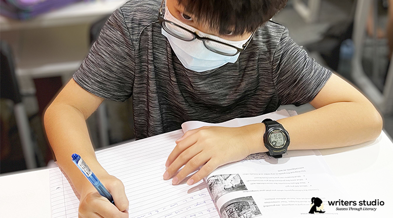 A Student Writing an Essay on their Notebook