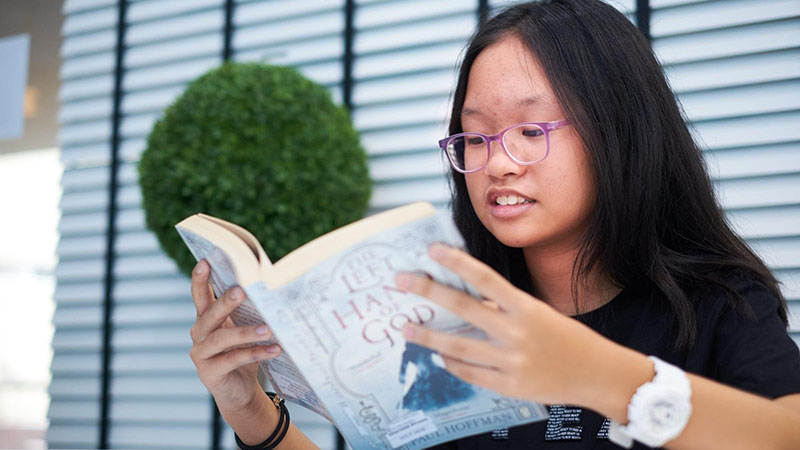 A student reading a book in Writers Studio library