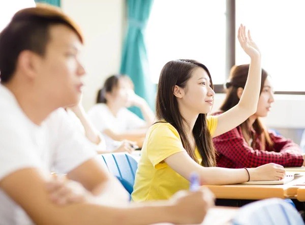 A student is raising her hand in a classroom